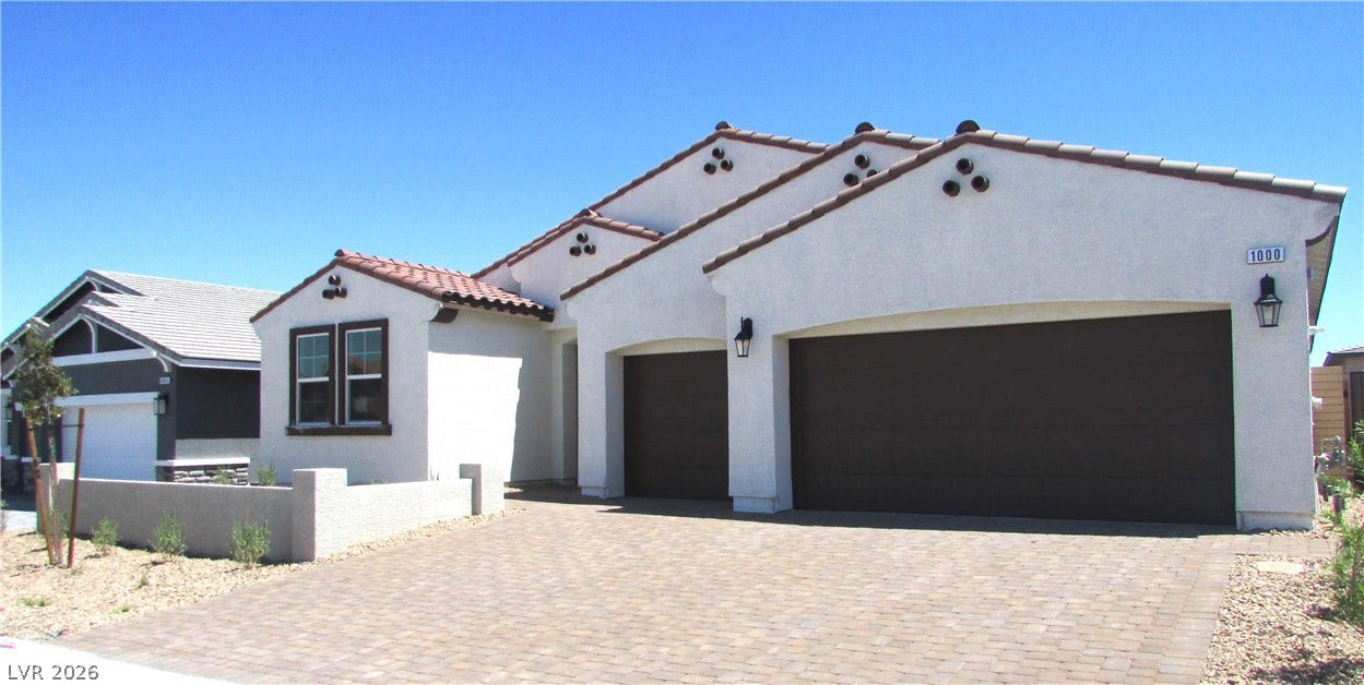 Spanish tile rooflines and a spacious paver driveway define this modern stucco exterior. Photo is of actual home.