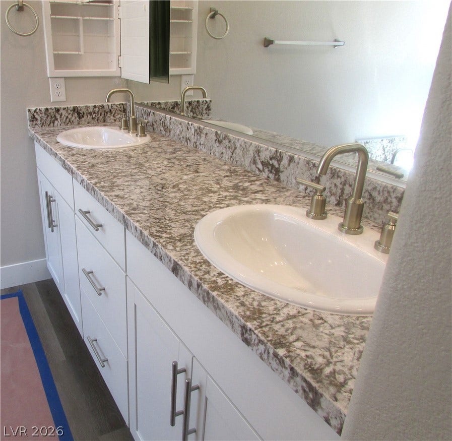 Gleaming stone countertops anchor a double vanity under modern fixtures. Photo is of actual home.