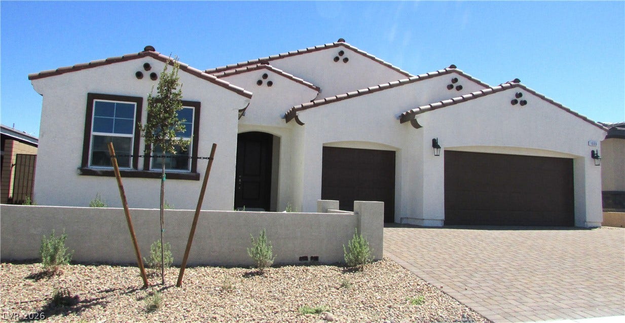 Stucco walls and a tiled roof define this modern Spanish-style home with a paved driveway. Photo is of actual home.