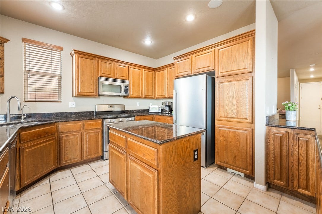 2439 Kaymin Ridge Road, Henderson, NV 89052 A well-appointed kitchen features rich wooden cabinetry, granite countertops, and modern stainless steel appliances.