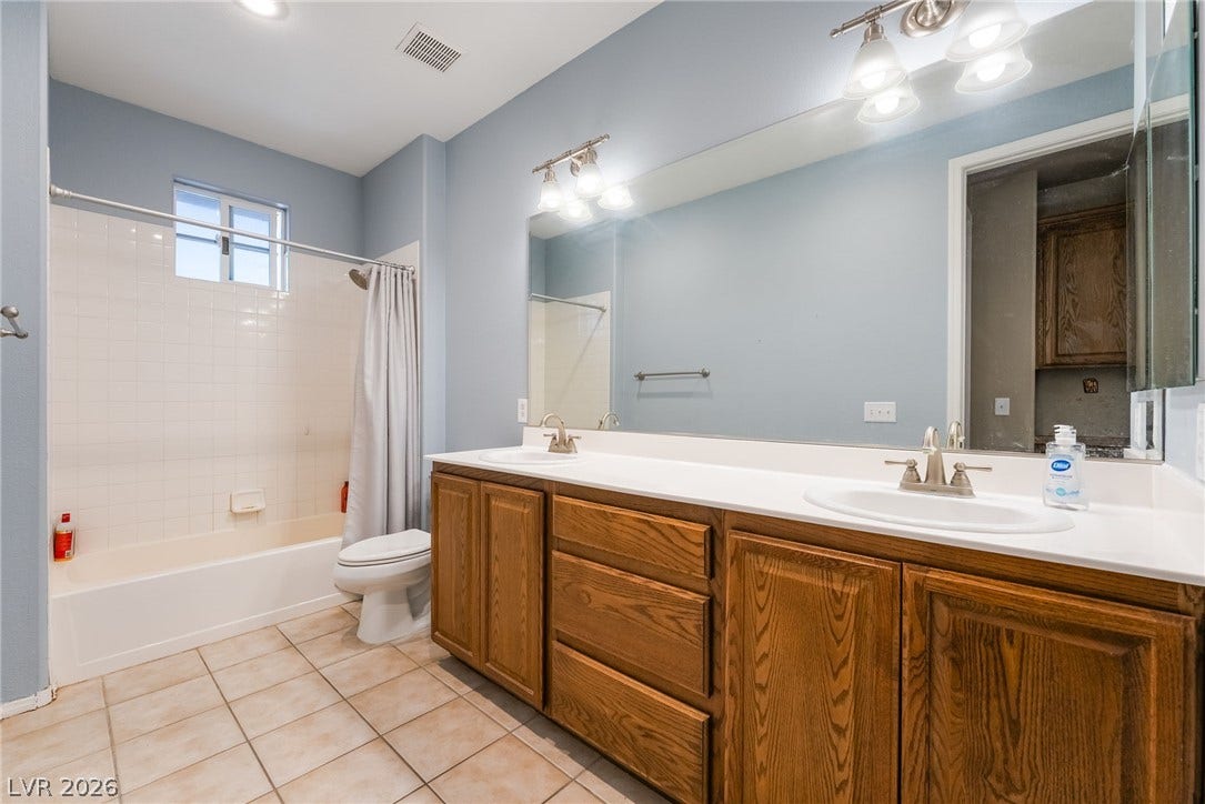2439 Kaymin Ridge Road, Henderson, NV 89052 Dual vanities and a tub/shower combo offer practical elegance in this well-appointed bathroom.
