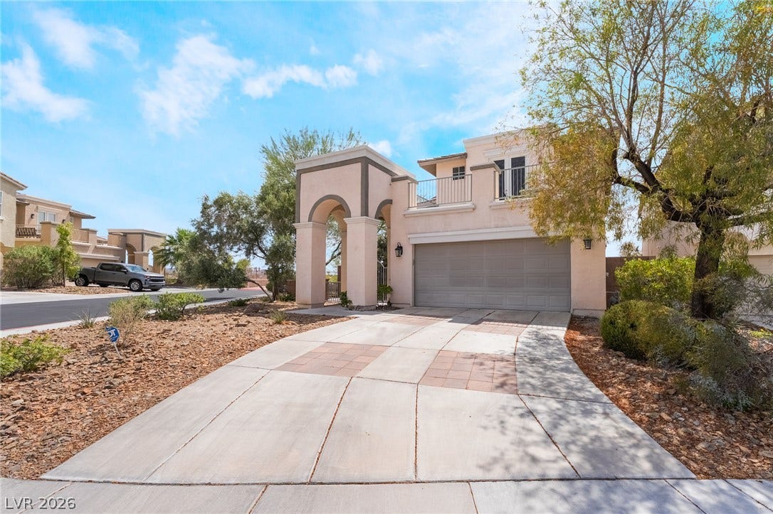 2439 Kaymin Ridge Road, Henderson, NV 89052 A striking desert-style residence with a distinguished arched entryway and a private second-story balcony.
