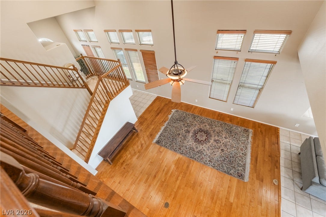 2439 Kaymin Ridge Road, Henderson, NV 89052 A grand, naturally illuminated living area showcases soaring ceilings, an elegant hardwood floor, and a striking staircase.