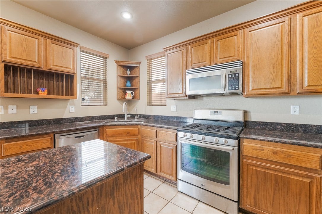 2439 Kaymin Ridge Road, Henderson, NV 89052 A functional kitchen features wood cabinetry, dark granite counters, and stainless steel appliances.