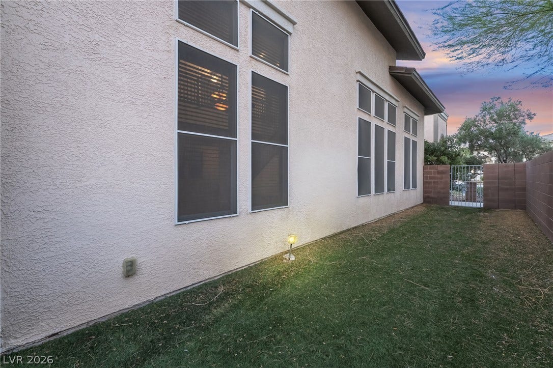2439 Kaymin Ridge Road, Henderson, NV 89052 A private, grassy yard featuring a secure gate and ample natural light from numerous windows.