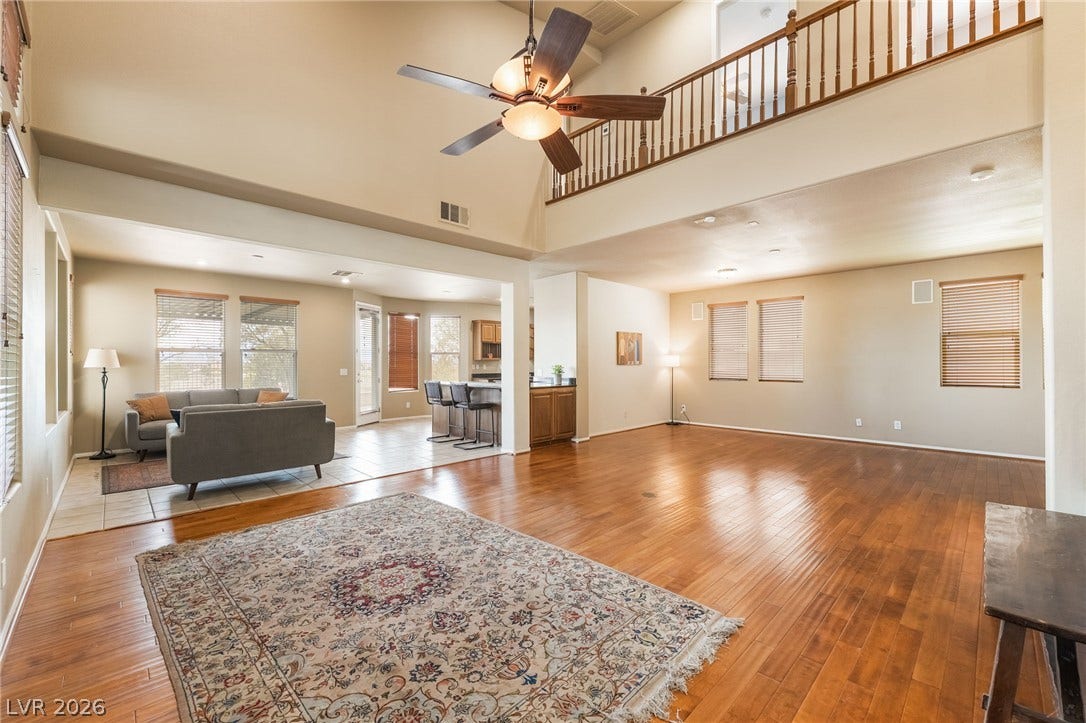 2439 Kaymin Ridge Road, Henderson, NV 89052 A spacious, naturally illuminated living area flows seamlessly into an open kitchen, featuring gleaming wood floors.