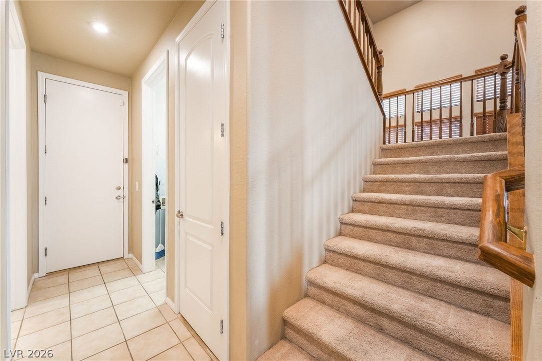 2439 Kaymin Ridge Road, Henderson, NV 89052 A welcoming entryway with tiled flooring leads to a plush carpeted staircase with a wooden banister.