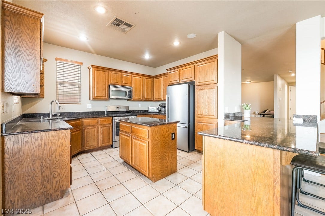 2439 Kaymin Ridge Road, Henderson, NV 89052 A well-appointed culinary space featuring ample wood cabinetry and dark granite countertops.