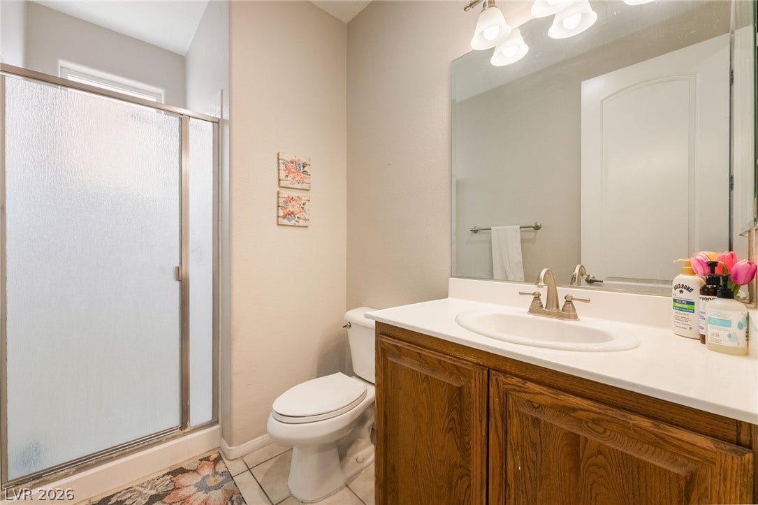 2439 Kaymin Ridge Road, Henderson, NV 89052 A compact bathroom offers a functional vanity with ample counter space and an adjacent shower stall.