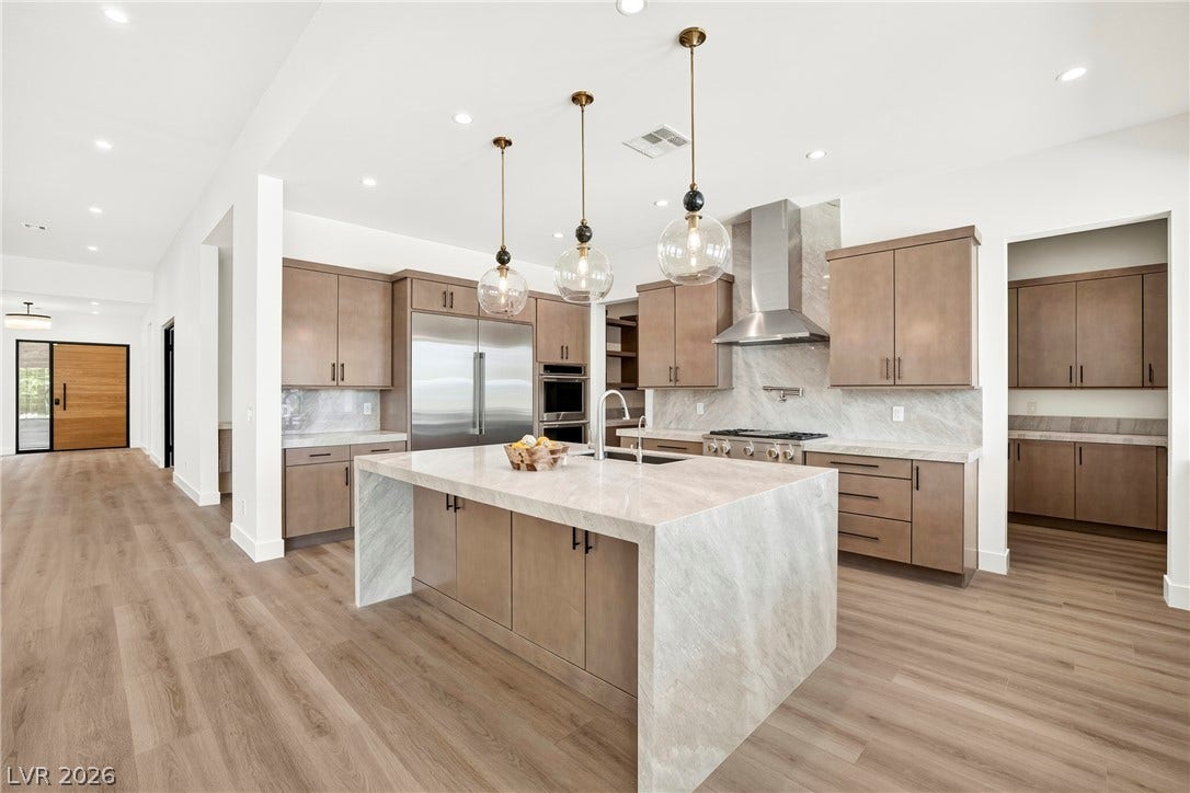 4360 Conough Lane, Las Vegas, NV 89129 A well-appointed kitchen showcases an expansive island with a waterfall counter, ample cabinetry, and state-of-the-art appliances, extending into an inviting open-concept living area.