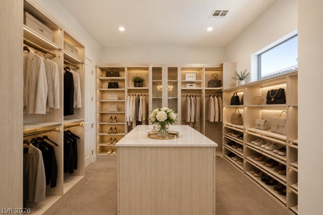 4360 Conough Lane, Las Vegas, NV 89129 Virtually Staged. Custom built-ins and a central island highlight this spacious walk-in closet with carpet flooring.