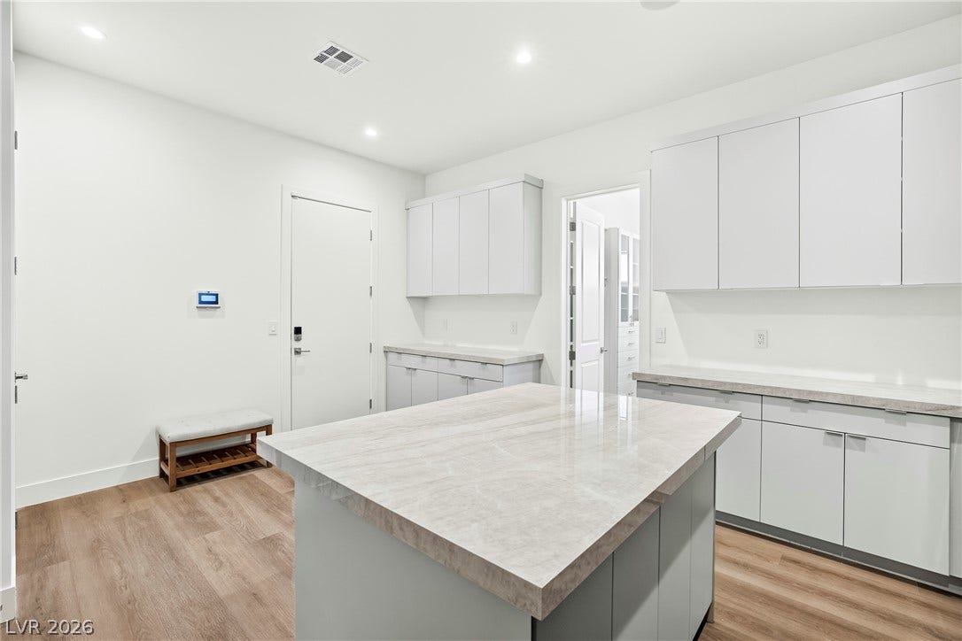 4360 Conough Lane, Las Vegas, NV 89129 A well-lit kitchen presents a spacious island with ample counter space, alongside sleek cabinetry and durable wood flooring.