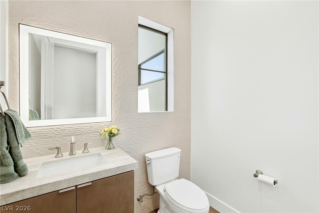 4360 Conough Lane, Las Vegas, NV 89129 A chic powder room features a sophisticated illuminated mirror and sleek vanity with a modern sink.