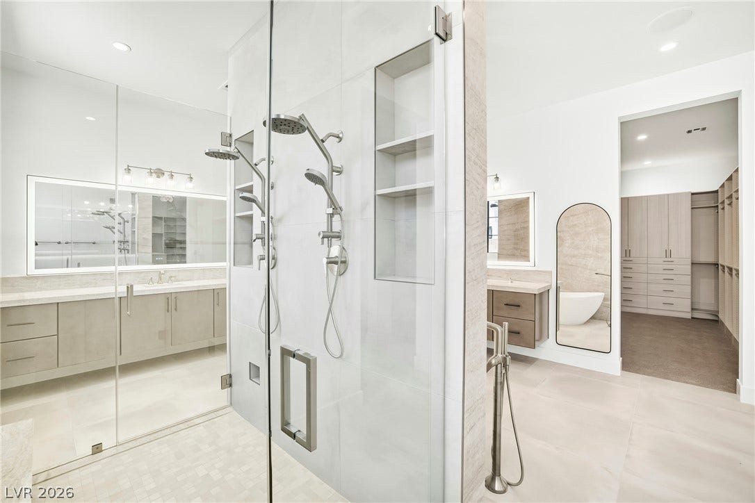 4360 Conough Lane, Las Vegas, NV 89129 A spacious primary bathroom boasts a walk-in shower with dual showerheads and a generously sized walk-in closet.