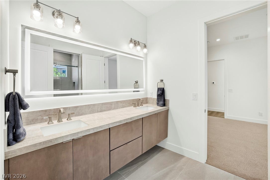 4360 Conough Lane, Las Vegas, NV 89129 A well-appointed primary bathroom showcases a double vanity with ample counter space and a large, illuminated mirror.