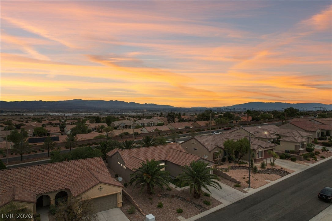 2141 Colvin Run Drive, Henderson, NV 89052 An aerial panorama reveals a residential neighborhood under a captivating desert sunset with distant mountains and city lights.
