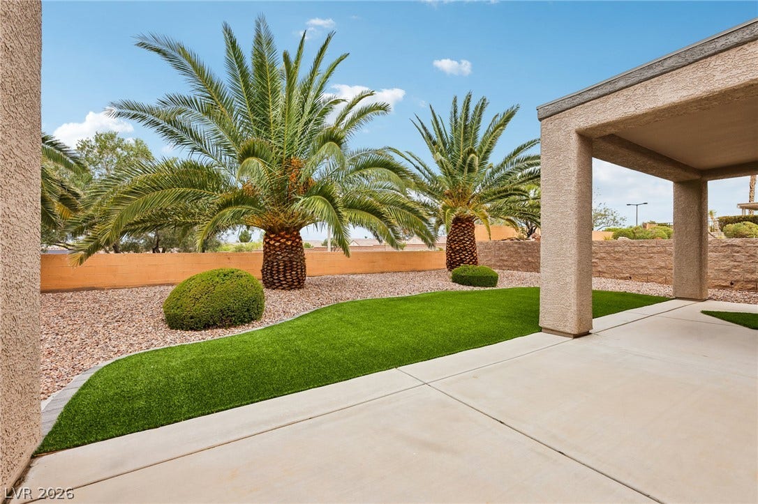 2141 Colvin Run Drive, Henderson, NV 89052 Lush artificial turf and mature palm trees define this tranquil outdoor space, perfect for relaxation.