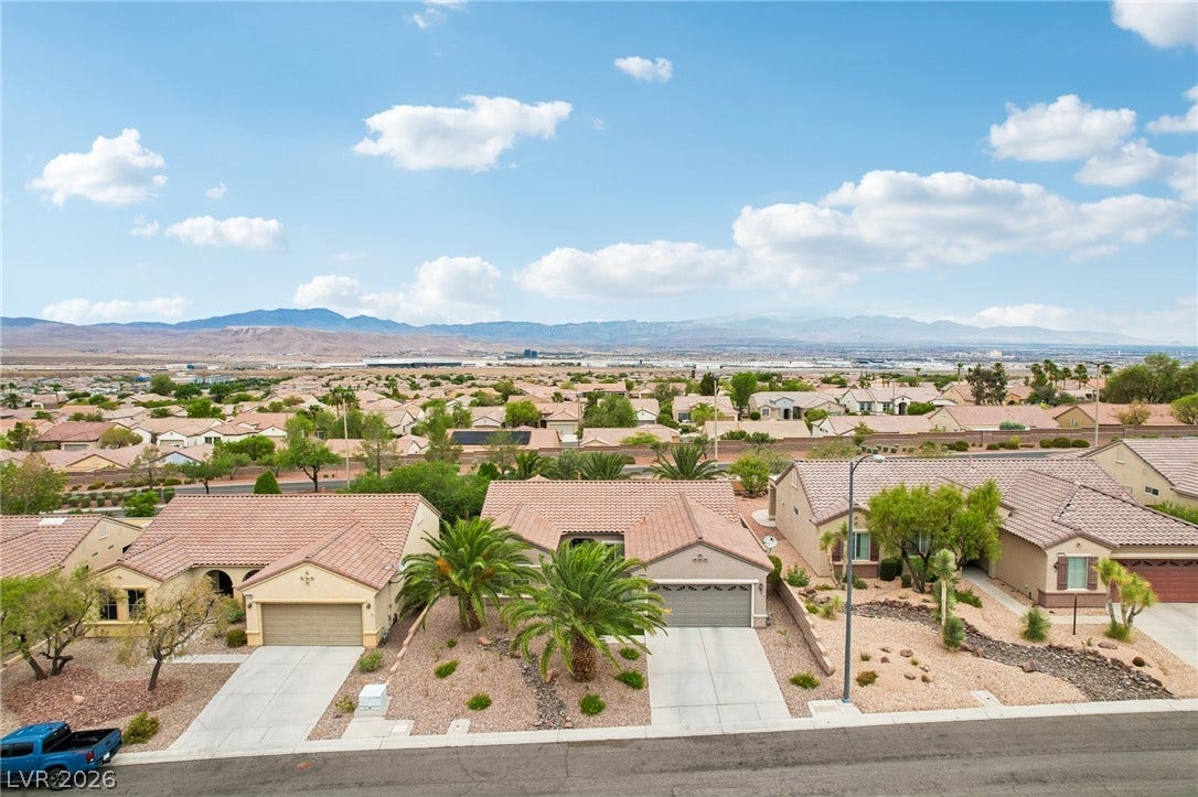2141 Colvin Run Drive, Henderson, NV 89052 An aerial perspective reveals a charming suburban home with desert landscaping and a tile roof, set against a distant mountain backdrop.
