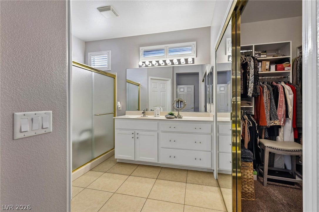 2141 Colvin Run Drive, Henderson, NV 89052 Step into a well-appointed primary bathroom featuring a vanity, a sleek shower, and a large adjacent walk-in closet.