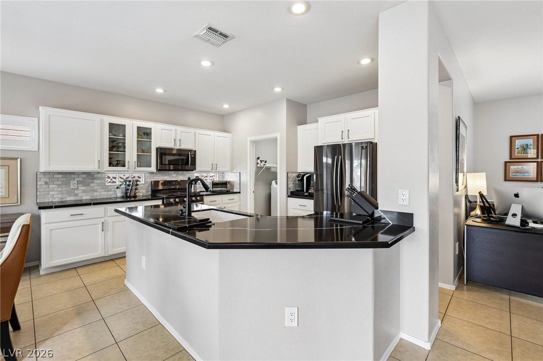 2141 Colvin Run Drive, Henderson, NV 89052 A contemporary kitchen features sleek quartz countertops, bright white cabinetry, and practical tile flooring.