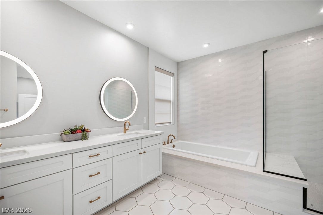 3194 Poplar Crest Court, Henderson, NV 89044 Dual vanities and a modern soaking tub offer a serene escape in this bright bathroom.