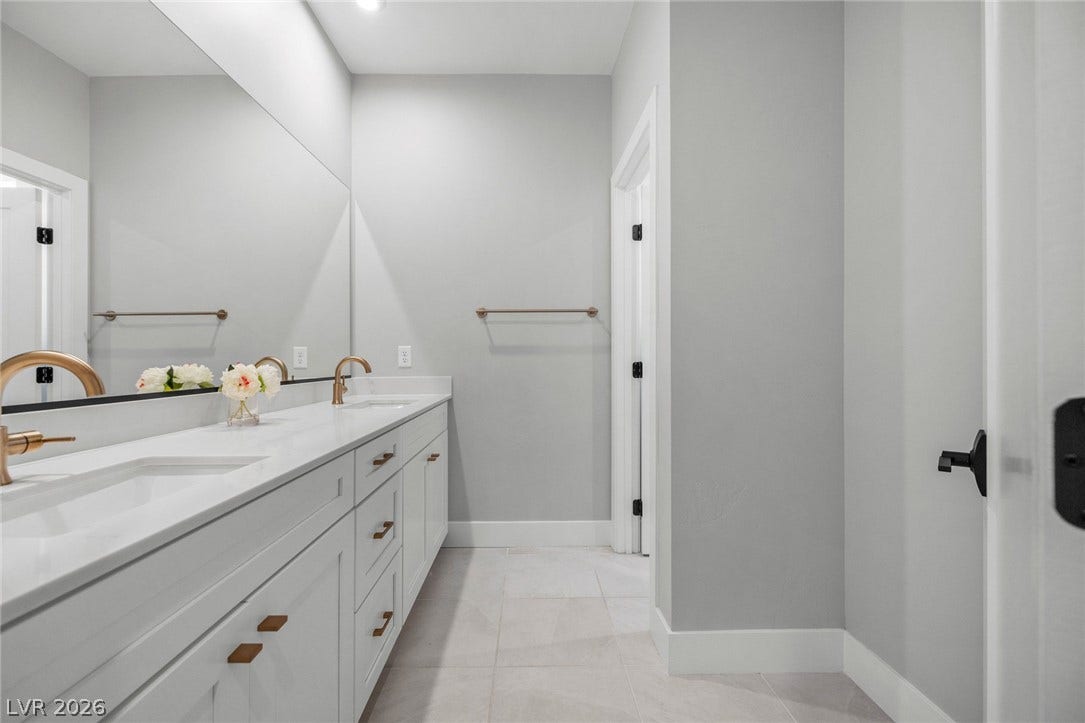 3194 Poplar Crest Court, Henderson, NV 89044 A well-appointed bathroom with a long double vanity, sleek modern fixtures, and neutral tiled flooring.