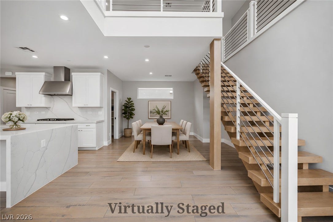 3194 Poplar Crest Court, Henderson, NV 89044 An open-concept interior features light hardwood floors, a contemporary kitchen, a dining area, and an elegant staircase.