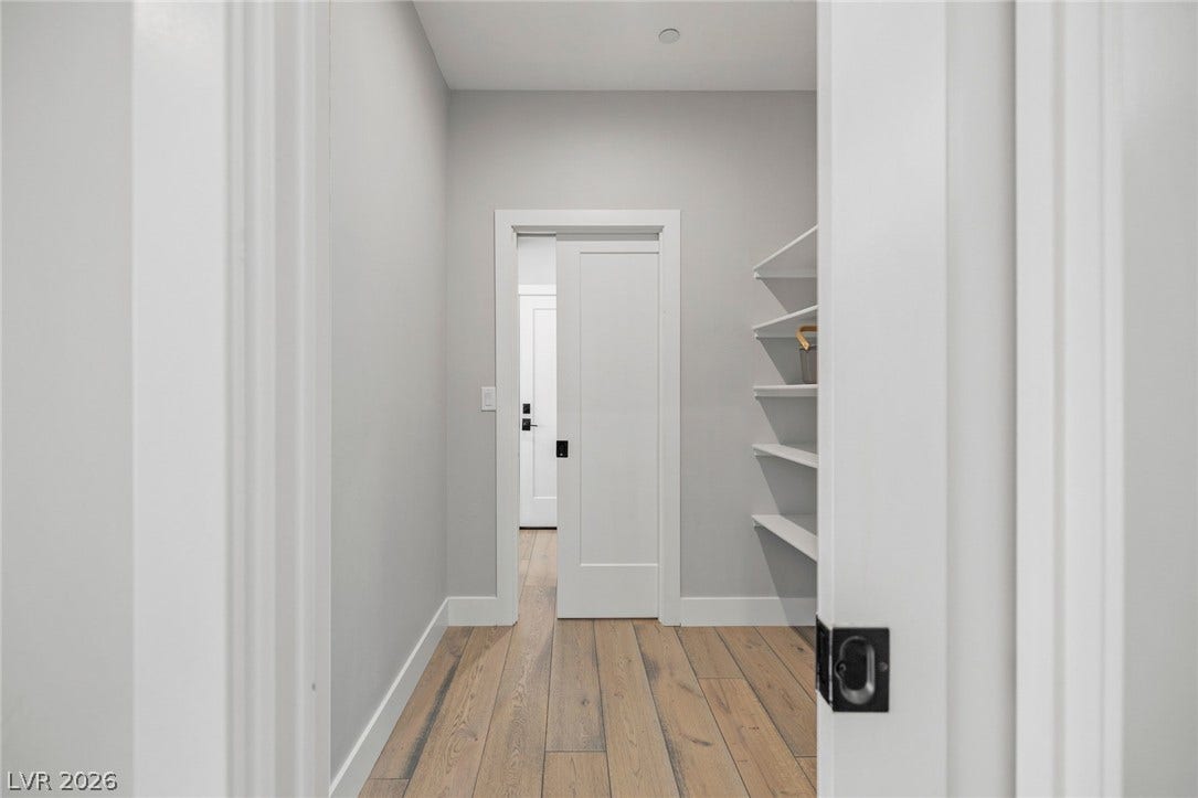 3194 Poplar Crest Court, Henderson, NV 89044 A well-lit hallway with natural wood flooring and ample built-in shelving provides practical storage and seamless transitions.