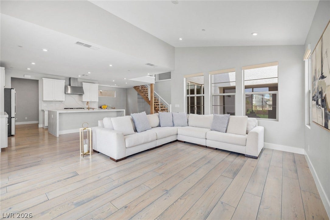 3194 Poplar Crest Court, Henderson, NV 89044 An open-concept living space with pale wood flooring offers ample natural light and a seamless flow into the modern kitchen.