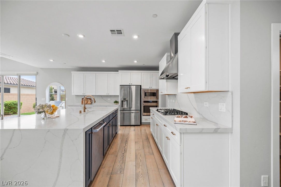 3194 Poplar Crest Court, Henderson, NV 89044 A well-lit culinary space showcases an expansive kitchen island with a deep sink and stainless steel appliances.