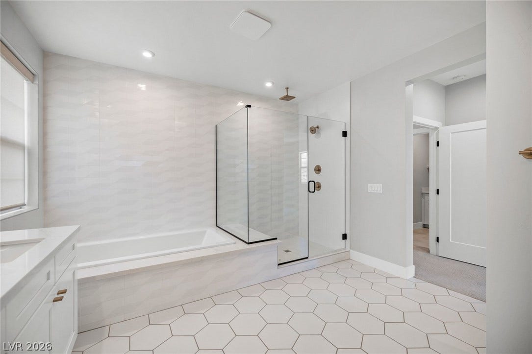 3194 Poplar Crest Court, Henderson, NV 89044 A well-appointed bathroom features a spacious glass-enclosed shower, a relaxing soaking tub, and striking hexagon tile flooring.