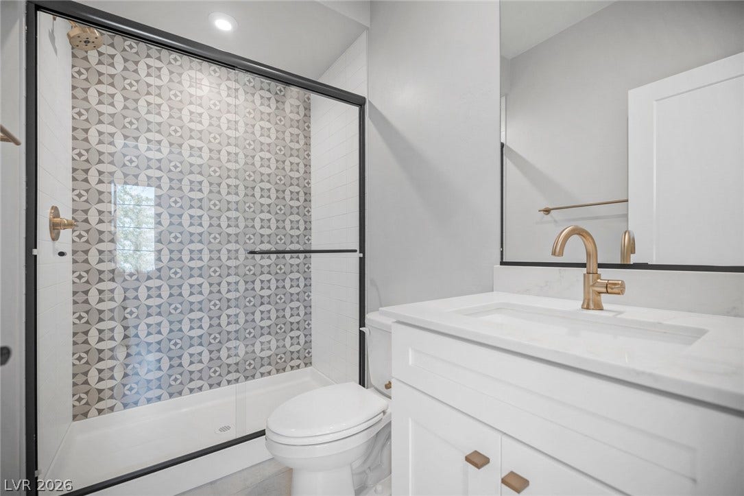 3194 Poplar Crest Court, Henderson, NV 89044 A well-appointed bathroom features a glass-enclosed shower with stylish geometric tile and a sleek vanity with modern fixtures.