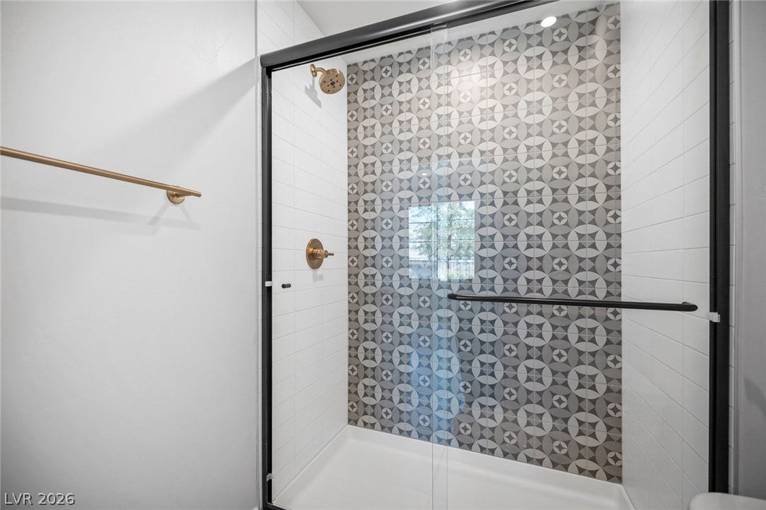 3194 Poplar Crest Court, Henderson, NV 89044 A modern shower with stylish geometric patterned tile and sleek bronze fixtures.