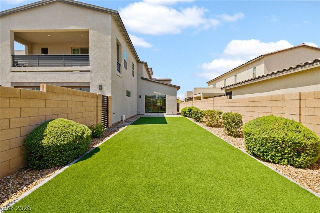 3194 Poplar Crest Court, Henderson, NV 89044 A private yard with vibrant green turf and an upstairs balcony offers a serene outdoor retreat.