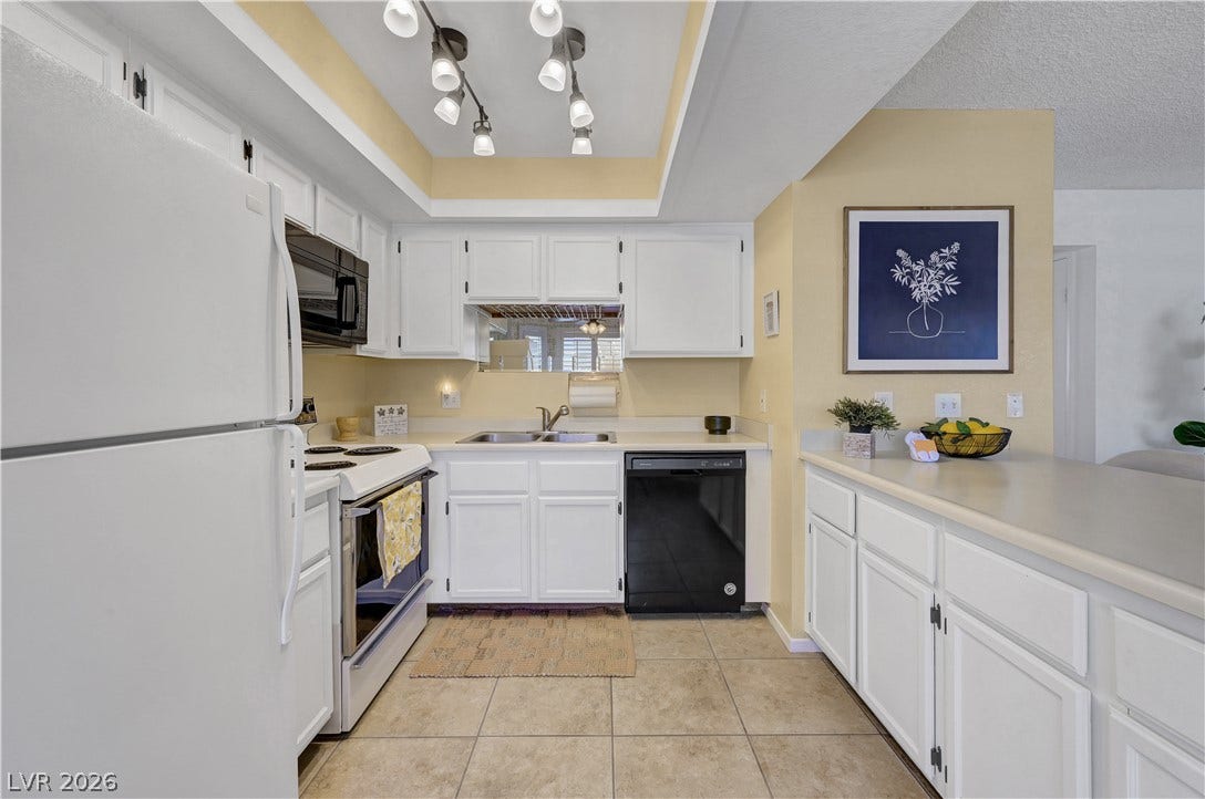 A well-equipped kitchen features white cabinetry and contemporary lighting.