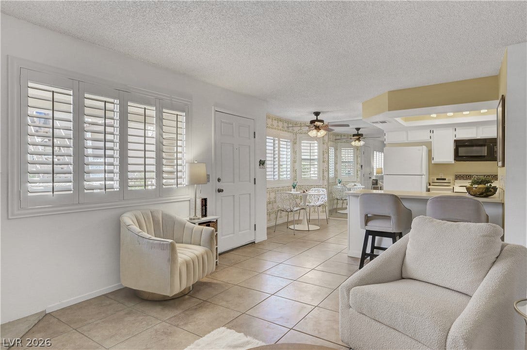 Functional kitchen with bar seating opens to a naturally illuminated living area with ample windows.