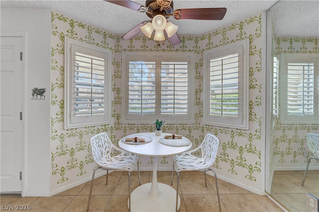 A charming breakfast nook features ample natural light and a decorative ceiling fan.