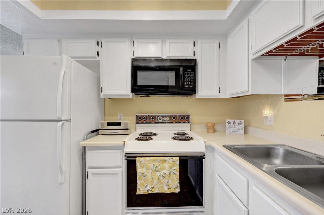 A well-appointed cooking space offers practical amenities and streamlined white cabinetry.