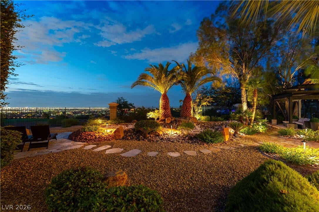 2676 Botticelli Drive, Henderson, NV 89052 Illuminated palm trees and landscaping offer a private oasis with captivating city views at dusk.