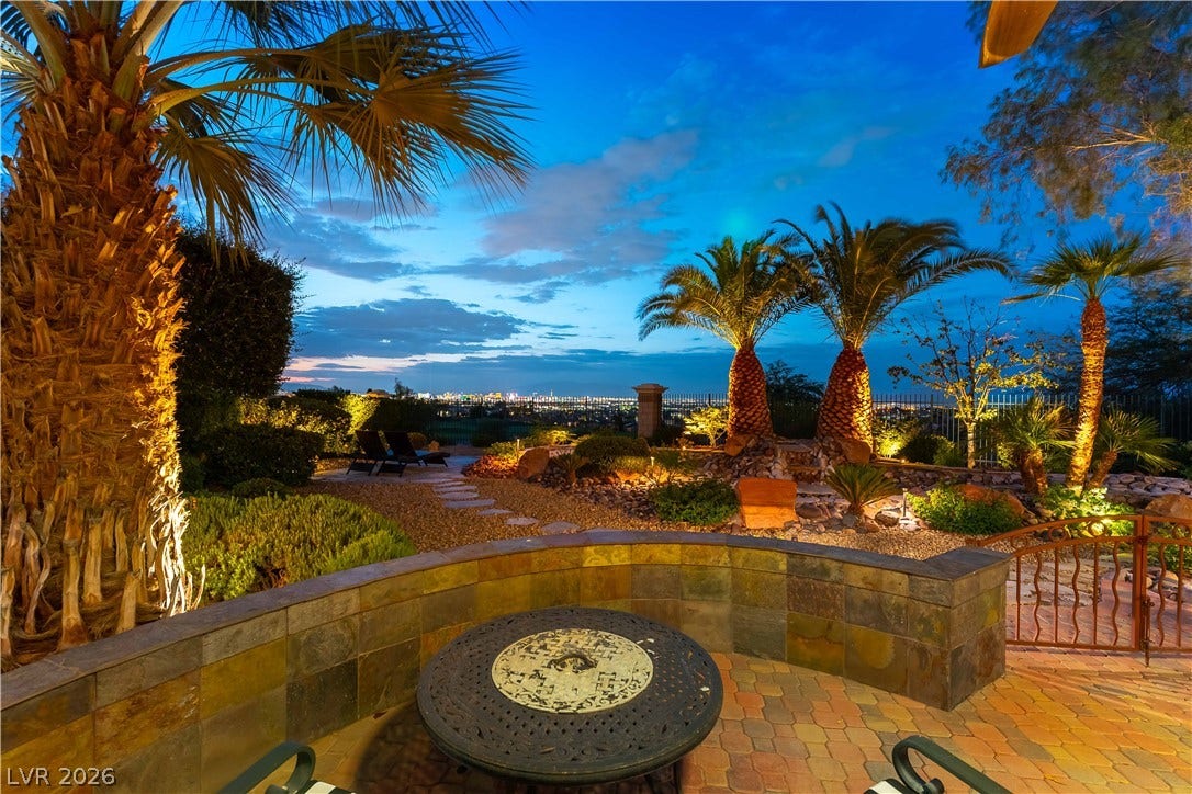 2676 Botticelli Drive, Henderson, NV 89052 City lights twinkle beyond this private patio, adorned with tropical palms and intricate hardscaping.