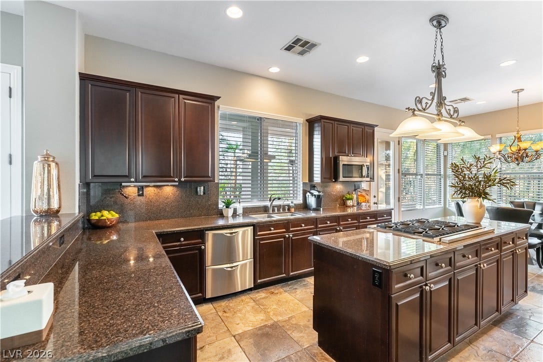 2676 Botticelli Drive, Henderson, NV 89052 A gourmet chef's kitchen boasts rich cabinetry, sparkling countertops, and an island with an integrated 6 burner cooktop.