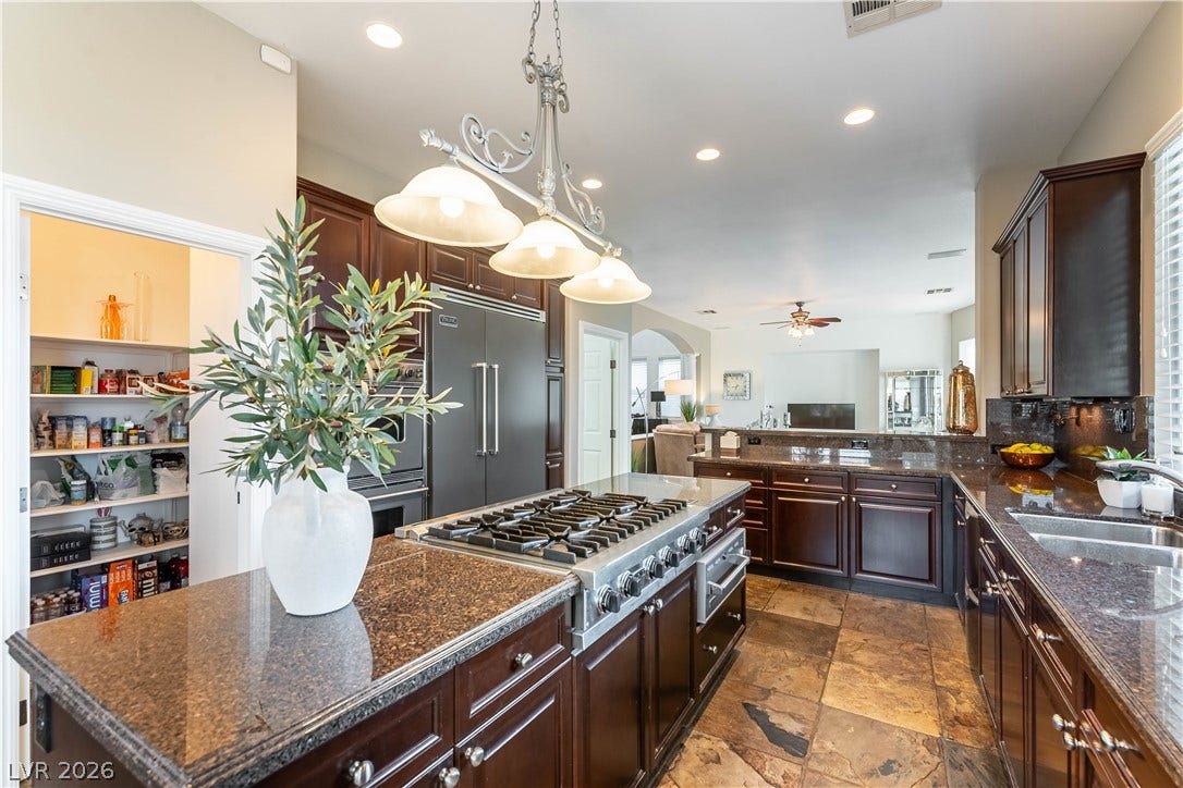 2676 Botticelli Drive, Henderson, NV 89052 An inviting kitchen with rich cabinetry, big walk-in pantry and stone flooring anchors the home's awesome layout.