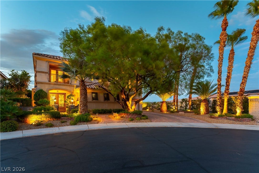 2676 Botticelli Drive, Henderson, NV 89052 Illuminated landscaping and mature trees enhance the inviting facade of this beautiful residence at dusk.
