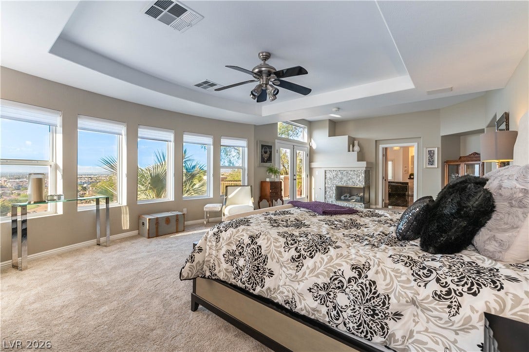2676 Botticelli Drive, Henderson, NV 89052 City views and a cozy fireplace create a perfect retreat in this bedroom with a coffered ceiling.
