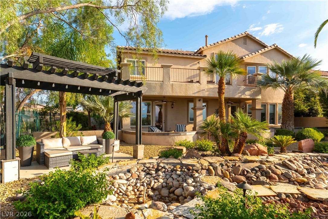 2676 Botticelli Drive, Henderson, NV 89052 A spacious backyard retreat features a pergola-covered patio with great views, lush landscaping, and a tiered rock water feature.