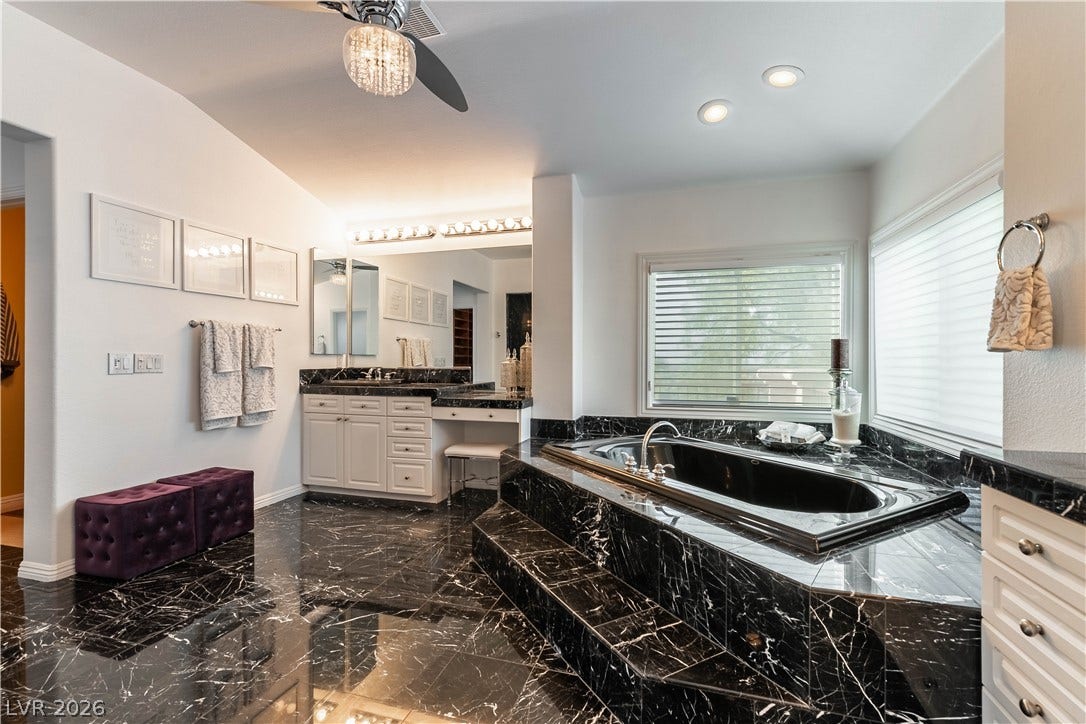 2676 Botticelli Drive, Henderson, NV 89052 Luxurious soaking tub that is jetted, walk-in stall shower, dual vanity sinks amidst polished black marble, crowned with recessed lighting and a ceiling fan.