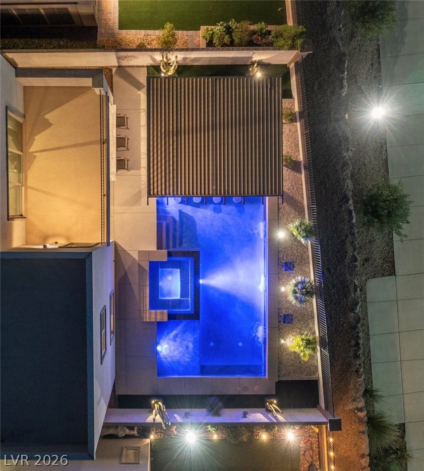 743 Glowing Horizon Street, Henderson, NV 89052 An aerial perspective reveals a serene pool and spa, illuminated for evening enjoyment, nestled beside a private patio.