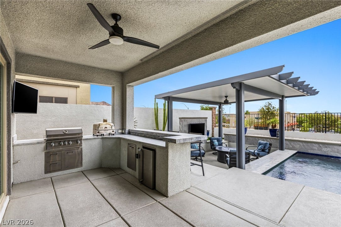 743 Glowing Horizon Street, Henderson, NV 89052 An inviting outdoor kitchen area with a built-in grill and covered patio for alfresco dining and relaxation by the pool.