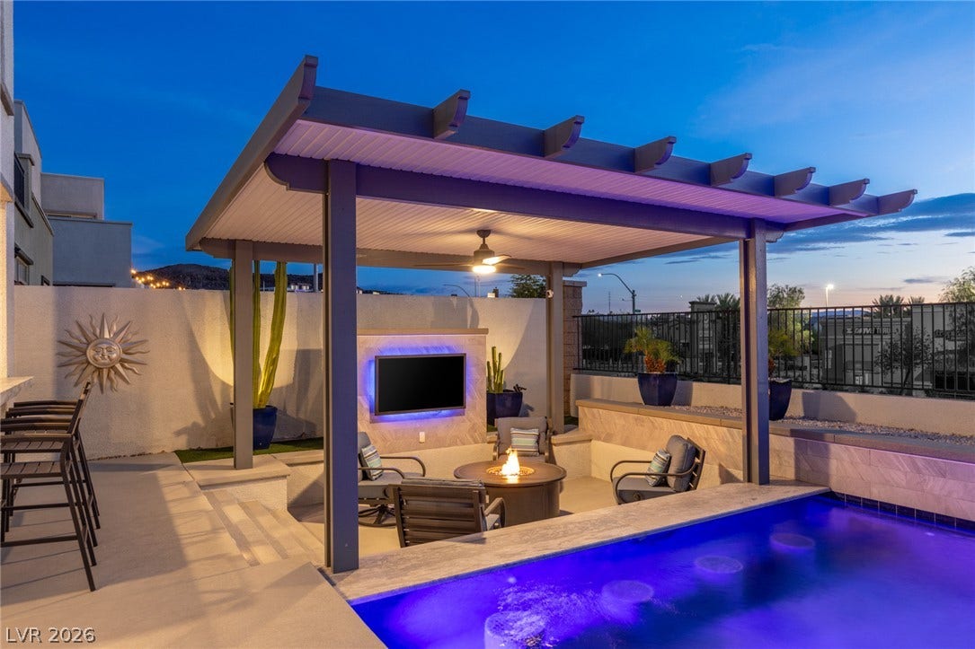 743 Glowing Horizon Street, Henderson, NV 89052 An inviting outdoor living area features a shimmering pool, cozy fire pit, and a covered patio for year-round enjoyment.