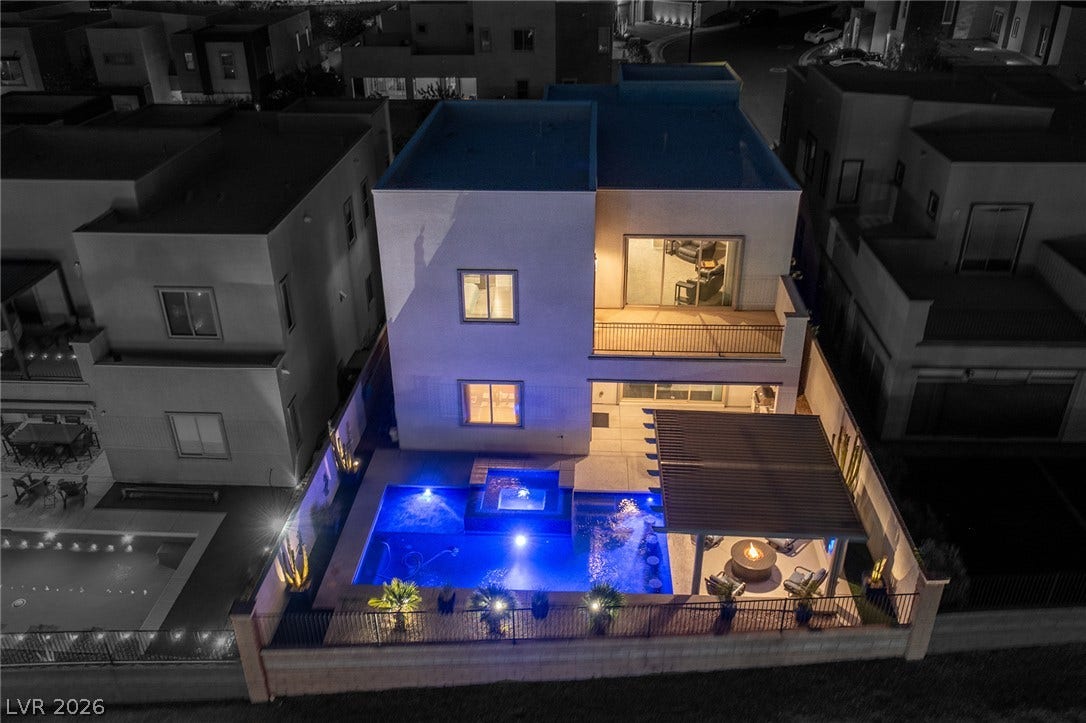 743 Glowing Horizon Street, Henderson, NV 89052 An illuminated backyard oasis boasts a sparkling pool, integrated spa, and shaded patio perfect for evening gatherings.